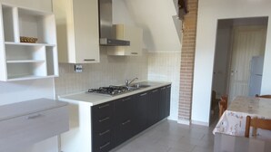 A modern kitchen with a gas stove, black cabinets, and a white countertop. - Large four-room apartment with swimming pool near the sea (Vada)