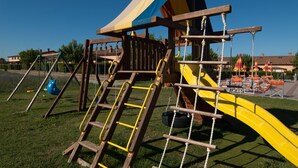 A playground with a yellow slide, climbing structures, and a blue and yellow roof. - Large four-room apartment with swimming pool near the sea (Vada)