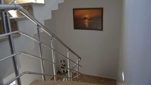 Una escalera con barandillas metálicas y un cuadro enmarcado de delfines en la pared.