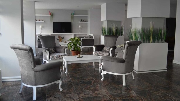 Una sala de estar moderna con sillones tapizados en gris, una mesa de centro blanca y un televisor de pantalla plana montado en la pared.
