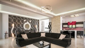 Ein modernes Wohnzimmer mit einem Ecksofa, einem Couchtisch und einer Küchenzeile mit roter Spritzschutzwand.