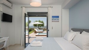 Ein Schlafzimmer mit einem Bett, einem Schreibtisch, einem Fernseher und Blick auf einen Pool sowie eine Außenlounge.