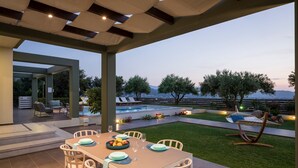 Eine Außenpatio mit einem Esstisch für sechs Personen, umgeben von Stühlen, einem Pool und Liegestühlen.