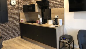 Una cocina moderna con pared de ladrillo, microondas, cafetera y televisor montado en la pared.
