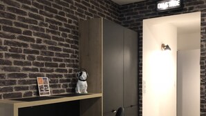 Una habitación moderna con pared de ladrillo, un escritorio de madera con dos sillas negras, un armario y una puerta con un cartel.