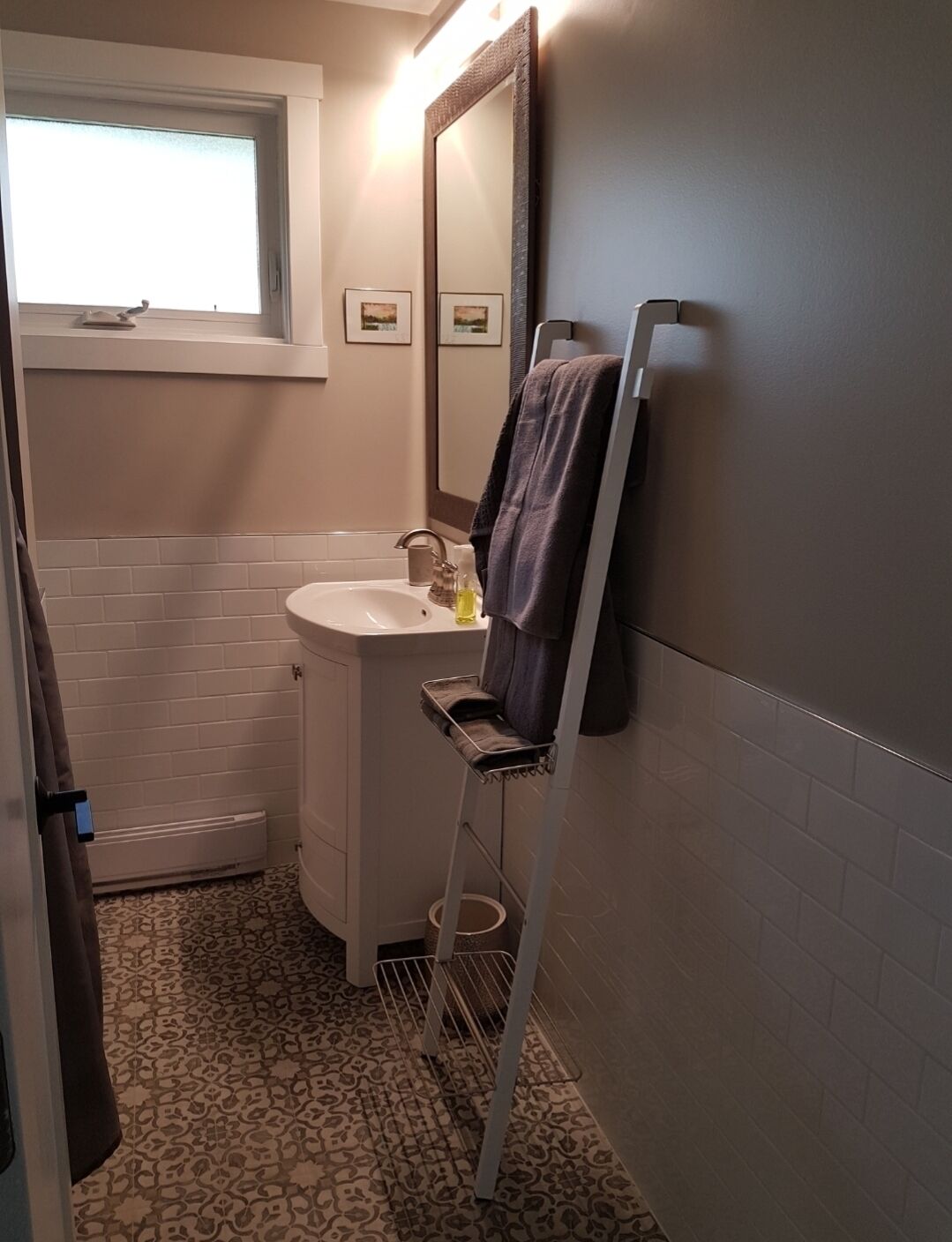 A bathroom with a white sink, a mirror, a towel rack, and a window.