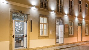 A building with multiple doors and windows, some with decorative ironwork, and a cobblestone street in front.