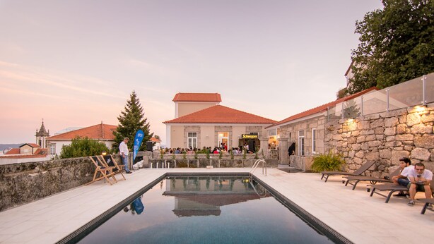 A swimming pool with lounge chairs and a stone building with a tiled roof.
