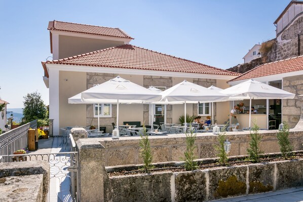 Una terraza en la azotea con asientos al aire libre, barandillas de piedra y vistas al mar.