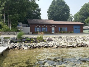 A building with a brown facade, a blue garage door, and a stone pathway leading to a dock over water.