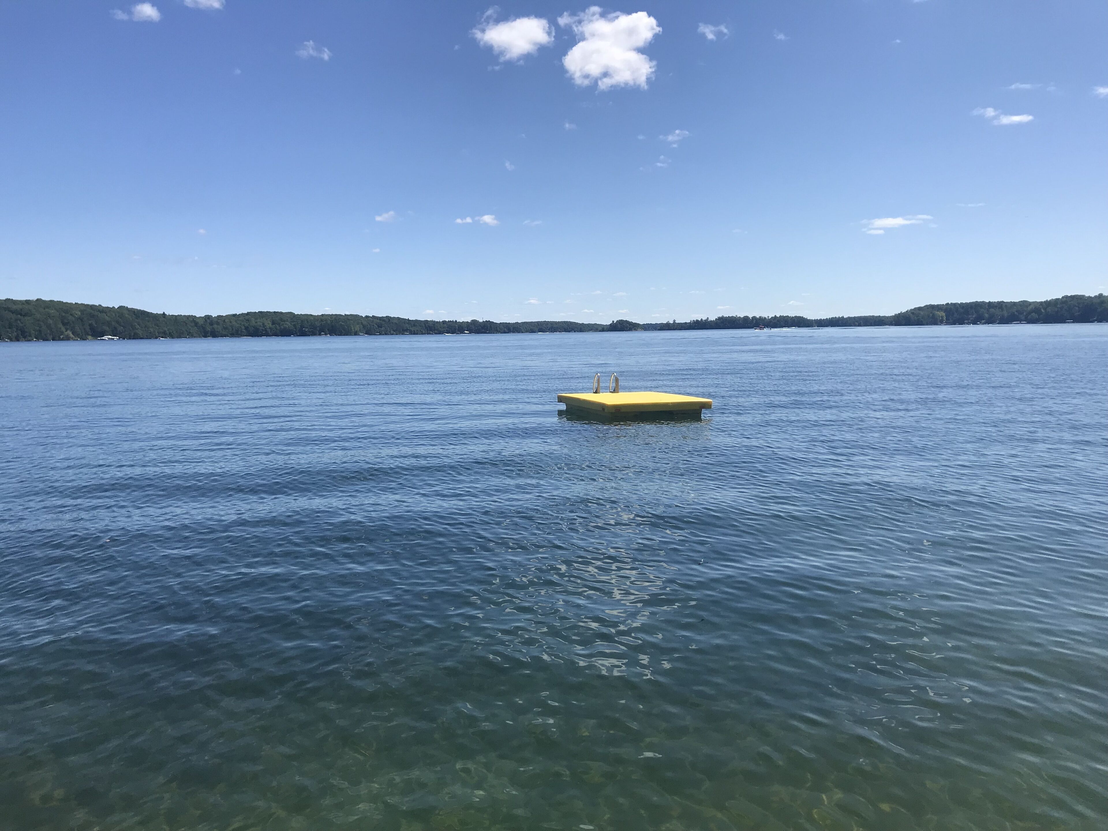 A clear view of a lake with a yellow dock extending into the water.