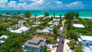 Eine Vogelperspektive eines Küstenwohngebiets mit Häusern, einer Straße und einem Strand im Hintergrund.