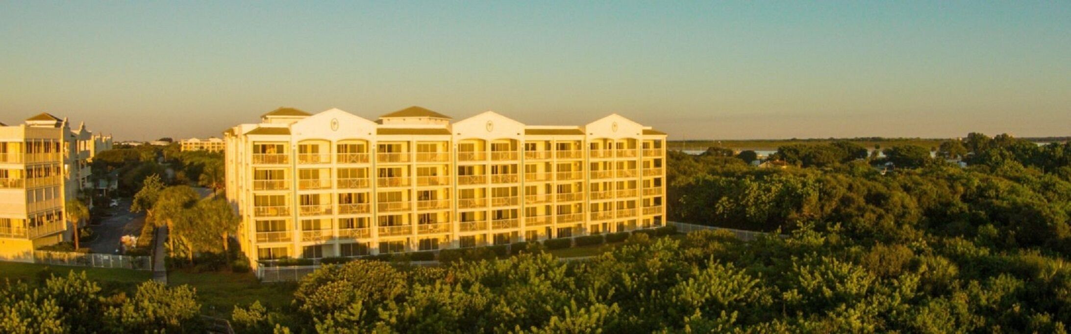 A large, multi-story hotel with a symmetrical facade, surrounded by lush greenery.