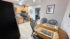 Una cocina moderna con armarios de madera, horno de acero inoxidable y un comedor con mesa redonda y cuatro sillas.