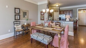A dining area with a wooden table, chairs, and a bench. There is a chandelier above the table.
