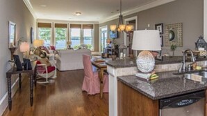 A spacious kitchen with a granite countertop, a dishwasher, and a dining area with a table and chairs.