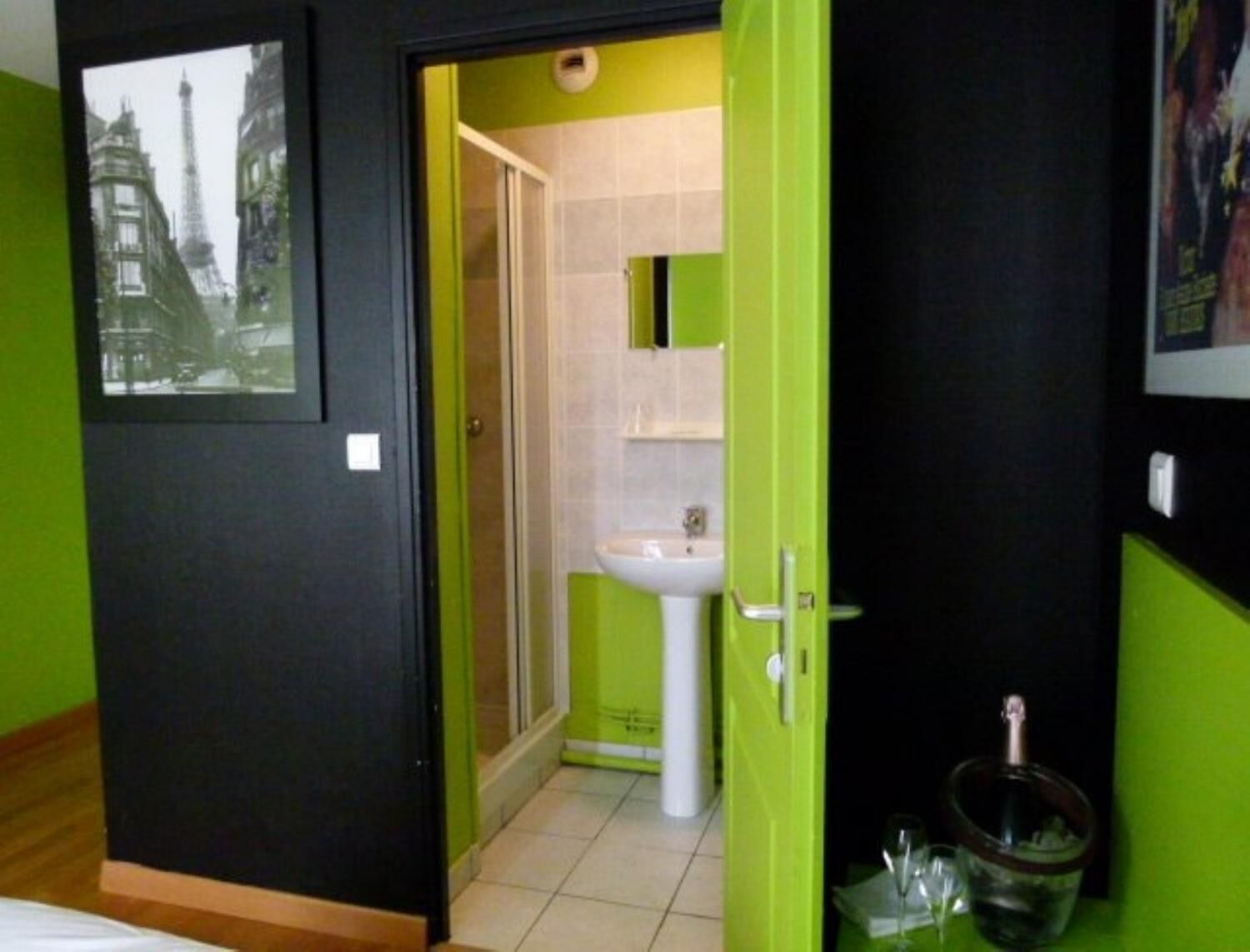 Una stanza con una porta verde che dà su un bagno con lavandino e specchio.