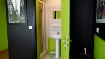 Una stanza con una porta verde che dà su un bagno con lavandino e specchio.