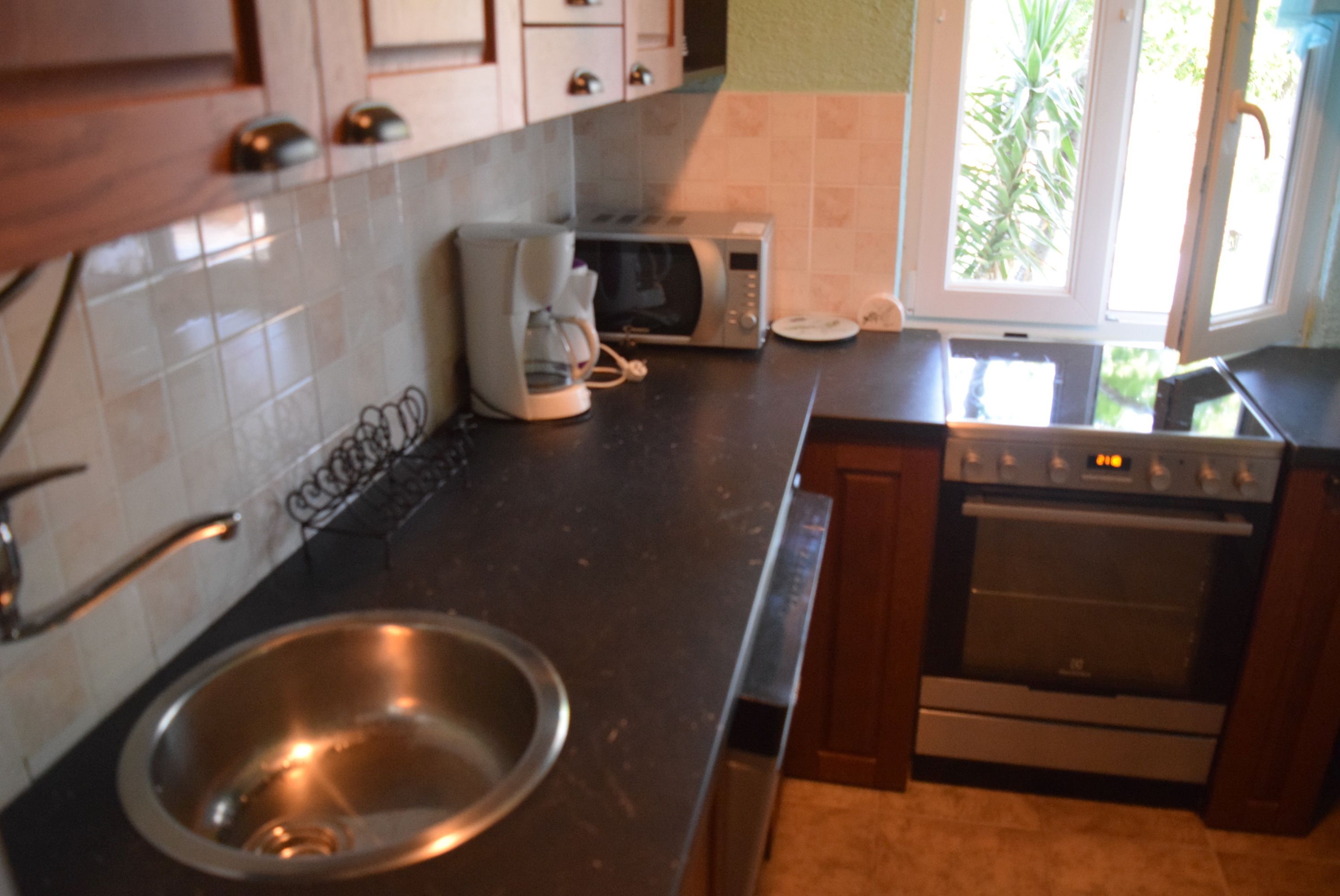 A kitchen with a stainless steel sink, a microwave, a toaster, and an oven.