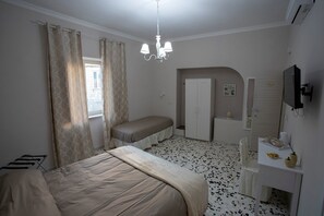 A bedroom with a bed, a bench, a wardrobe, a desk, and a TV. - B&B Agorà Mura Greche (Naples)