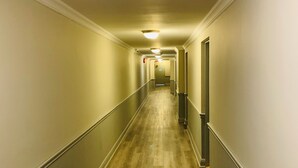 A long, narrow hallway with a wooden floor, white walls, and a metal railing on one side. - London Residency Inn (London)