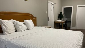 A neatly made bed with white bedding, a wooden headboard, and a small table with a Christmas tree. - London Residency Inn (London)