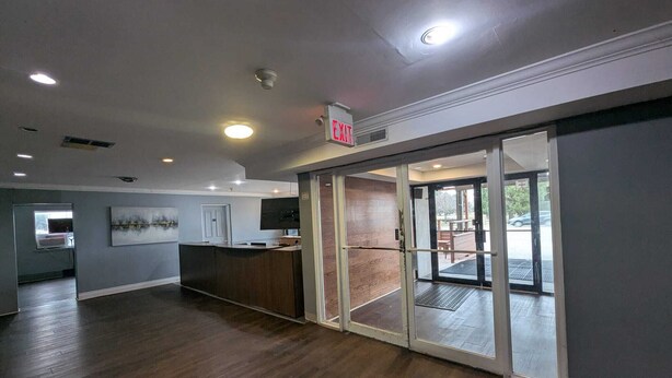 A spacious lobby with a reception desk, a glass door entrance, and a ceiling with recessed lighting. - London Residency Inn (London)