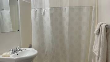Un baño con una bañera blanca, un lavamanos blanco con un espejo encima y una toalla colgada en la pared.