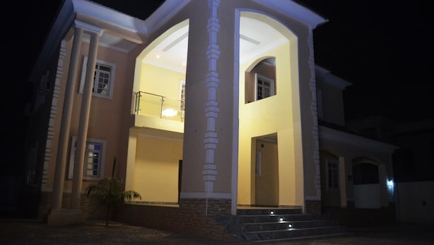 A two-story house with a central archway and a balcony. - House X (Abuja)