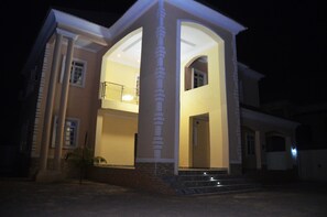 A two-story house with a central archway and a balcony. - House X (Abuja)