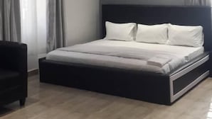 A bedroom with a bed, a chair, and an air conditioning unit. - House X (Abuja)