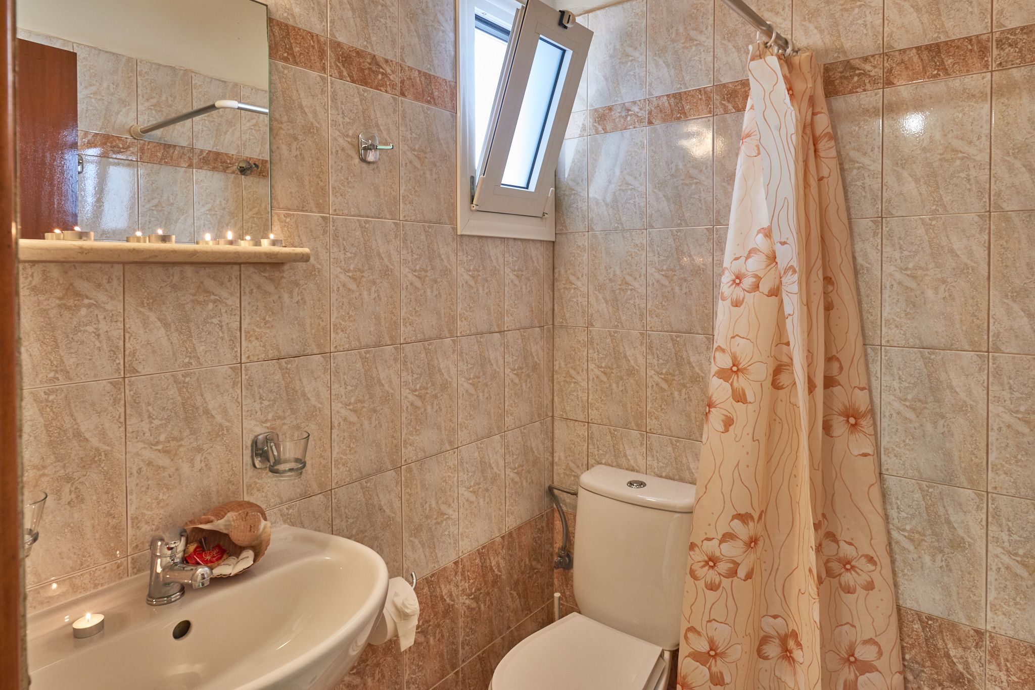 A bathroom with a sink, mirror, toilet, and shower curtain.