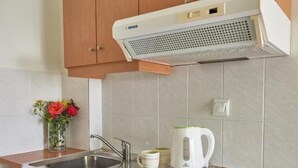 A compact kitchen with a built-in stove, a sink, and a range hood. - Corali Studios (Agios Vasileios)