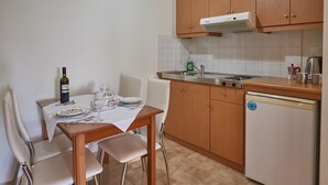 A small kitchen with a dining table, chairs, a refrigerator, and a sink. - Corali Studios (Agios Vasileios)