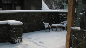 Un muro de piedra con techo nevado y un banco de madera.