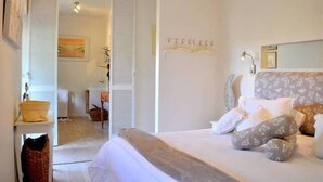 Een slaapkamer met een bed, nachtkastje, lamp en een decoratieve wandversiering.