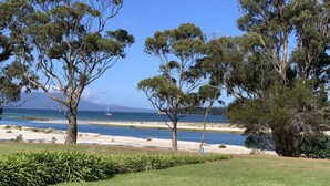 A coastal landscape with trees, a sandy beach, and a clear blue sky. - Orford Beach House - Orford.  (Orford)