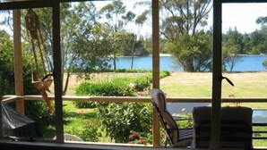 A room with a view of a lake, a chair, and a table. - Orford Beach House - Orford.  (Orford)
