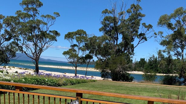 A wooden deck with two chairs and a table, overlooking a beach and ocean. - Orford Beach House - Orford.  (Orford)