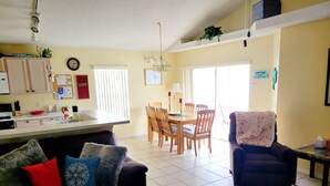 A living room with a sofa, a coffee table, and a dining area with a table and chairs. - Newly Updated Spacious 3 Bedroom Home With Pool, - near Disney (Davenport)