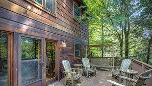 A wooden deck with Adirondack chairs and a glass door. - Relaxing, Cozy, Beautiful 3 BR Log Cabin in Blowing Rock/Boone NC (Blowing Rock)
