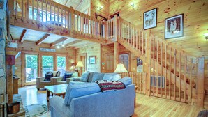 A spacious cabin with a loft area, a cozy living room with a blue sofa, and a wooden staircase. - Relaxing, Cozy, Beautiful 3 BR Log Cabin in Blowing Rock/Boone NC (Blowing Rock)