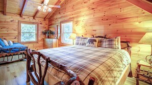 A wooden cabin bedroom with a bed, a dresser, a chair, and a ceiling fan. - Relaxing, Cozy, Beautiful 3 BR Log Cabin in Blowing Rock/Boone NC (Blowing Rock)
