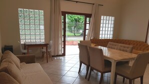 Un salon spacieux avec un grand canapé, une table à manger avec des chaises et une vue à travers la porte vitrée.