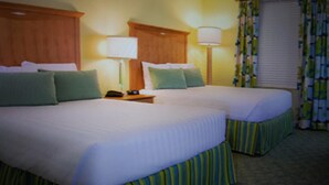 A hotel room with two beds, a nightstand with a telephone, and a window with curtains.