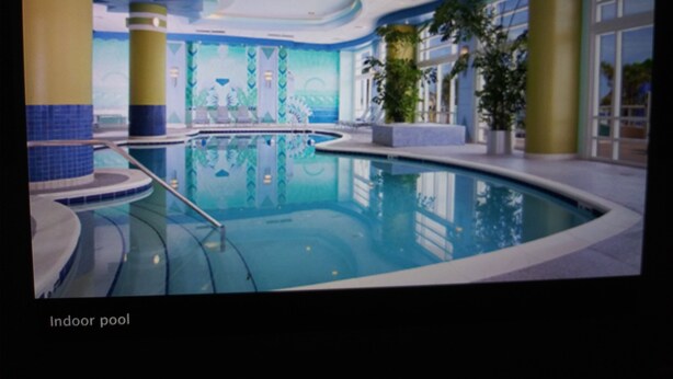 An indoor pool with clear water, surrounded by blue and yellow pillars, and a mural on the wall.