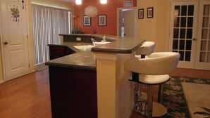 Una cucina con zona bar, pavimento in legno e una porta con decorazioni floreali.