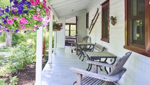 A porch with wooden benches and hanging flower baskets. - Modern Farmhouse on pristine private 12 Acres (Wallkill)