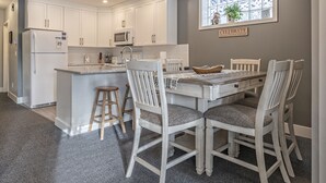 Una cocina con armarios blancos, una isla central y una mesa de comedor con cuatro sillas.