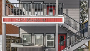 Un edificio de dos pisos con un balcón, una puerta roja y una escalera.